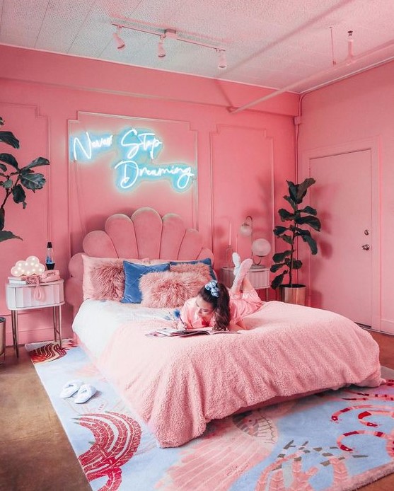 a glam pink bedroom with bright pink walls, a pink upholstered bed and pink nightstands plus a whimsy rug with pink