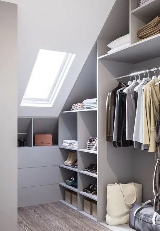 a grey attic closet with open storage compartments, drawers and railings plus a skylight for more natural light