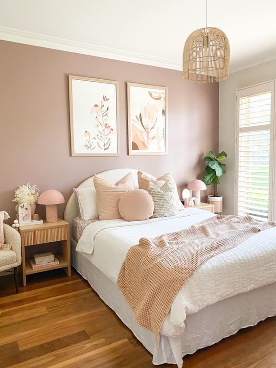 a lovely bedroom with a mauve accent wall, a white upholstered bed and neutral bedding, a mini gallery wlal, fluted nightstands