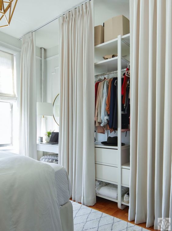 a makeshift closet with rails and drawers, open shelves hidden with curtains for a neat and stylish look
