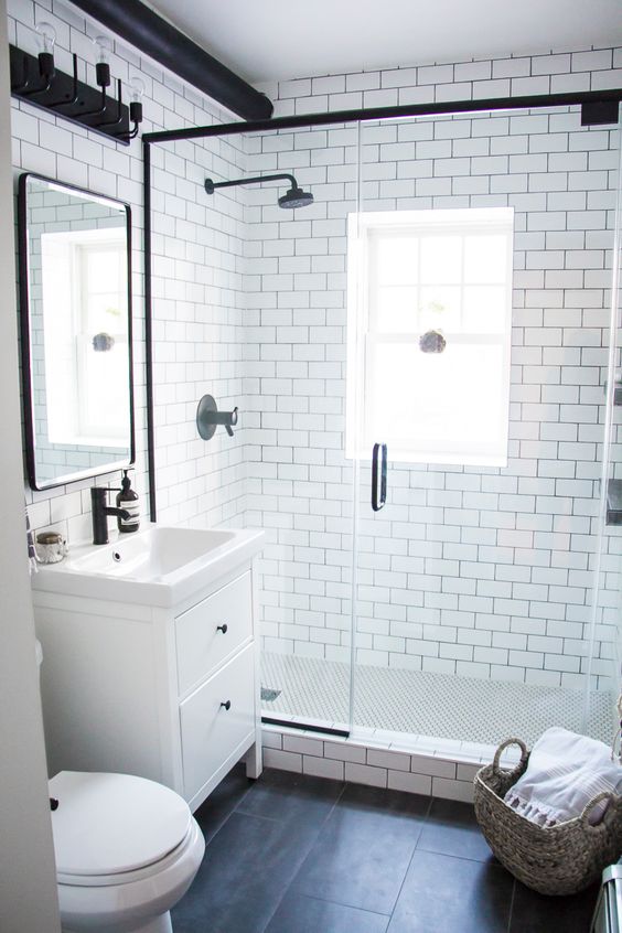 a modern monochromatic bahtroom with white subway tiles and black ones, a white vanity and black fixtures here and there