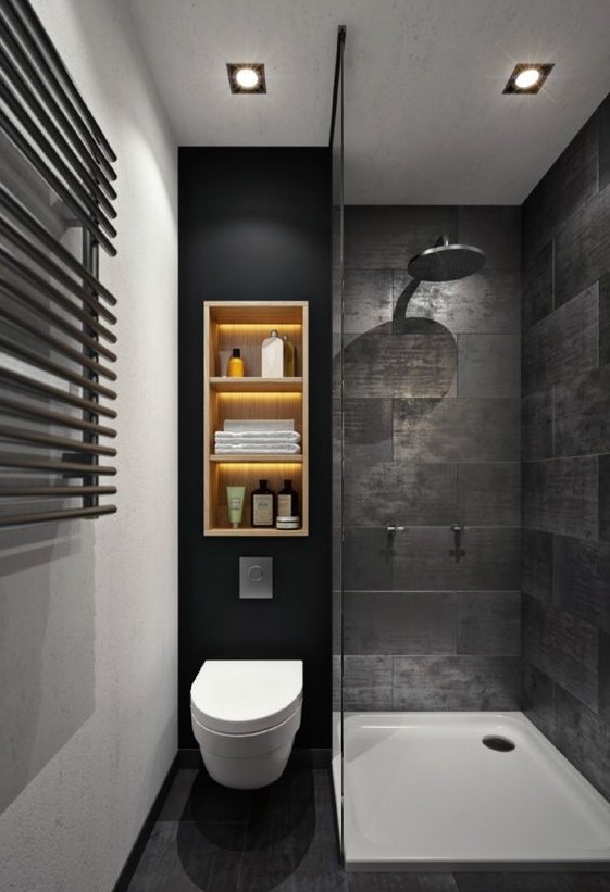 a moody black bathroom with stone-inspired tiles, a wall shelf with lights, a shower space
