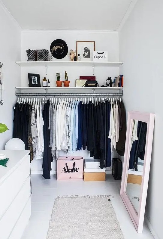 a neutral closet with a large rack, wall-mounted shelves, a white IKEA dresser, a mirror in a pink frame and some decor