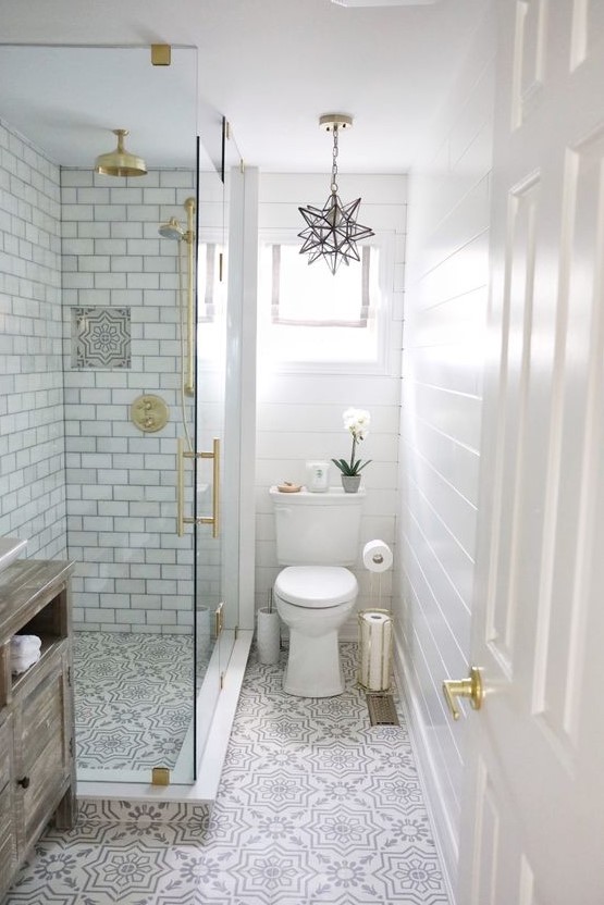 a neutral small bathroom with beadboard, printed tiles, subway tiles in the shower, gold touches and a star-shaped chandelier