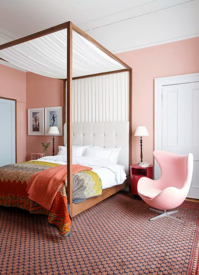 a pink bedroom with a cnaopy bed and bright bedding, a light pink Egg chair, mismatching nightstands and table lamps