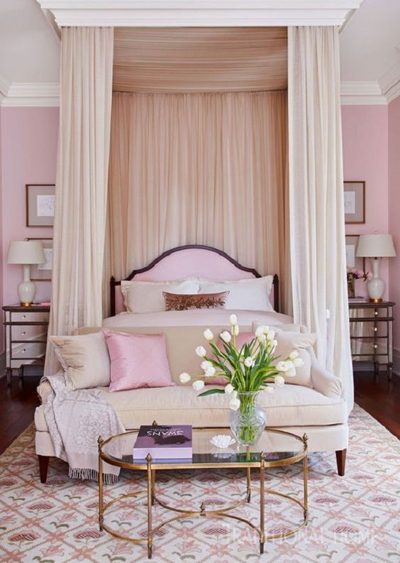 a refined light pink bedroom with a canopy bed and pink and neutral bedding, a neutral sofa and pillows, mirror nightstands