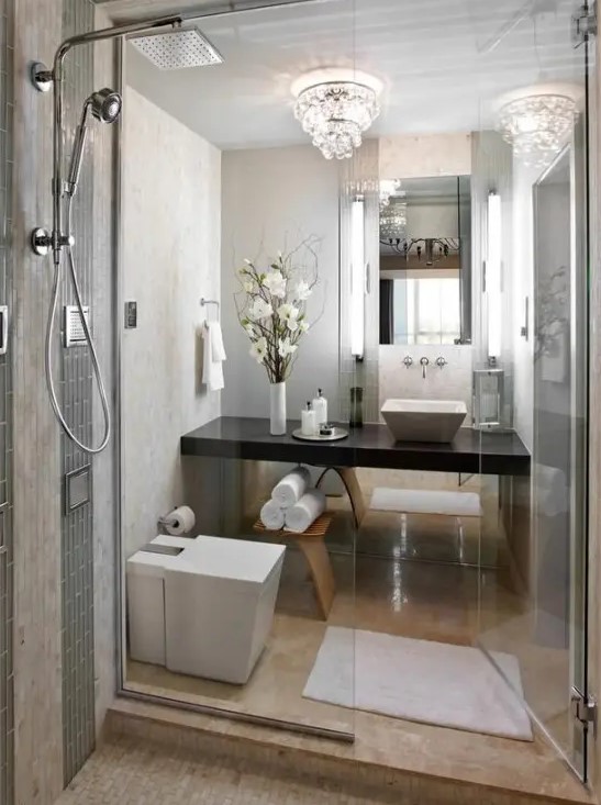 a refined small bathroom with stone tiles, a crystal chandelier, a shower space and a built-in dark vanity