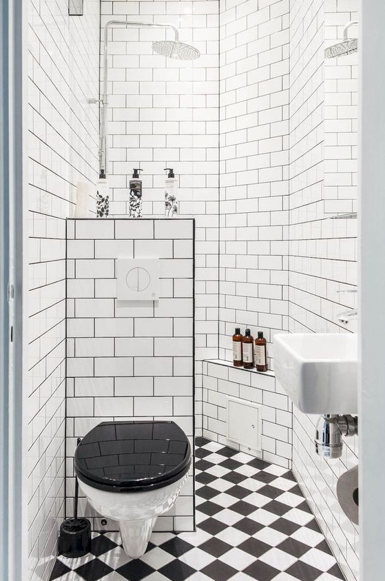 a retro-inspired black and white bathroom with a shower space, a mosaic tile floor and a half wall