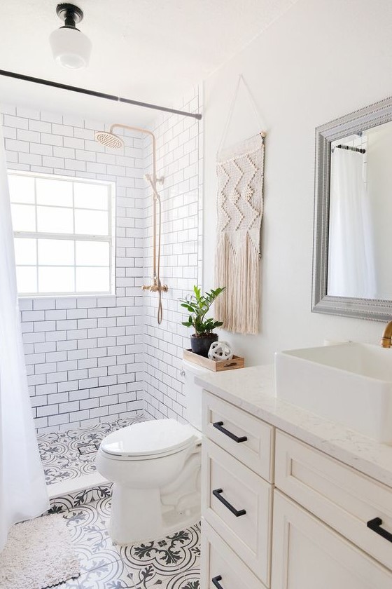 a small and neutral boho bathoom with white subway tiles and black and white ones, a farmhouse vanity, a macrame hanging and touches of black