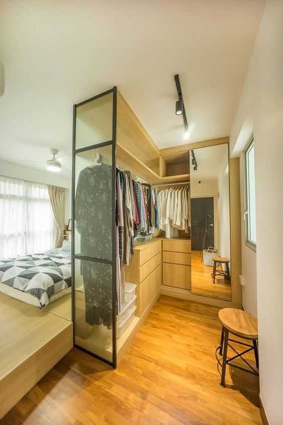 a small and cool closet with a glass wall, rails with hangers, some drawers and a mirror cabinet is a very edgy idea for a bedroom