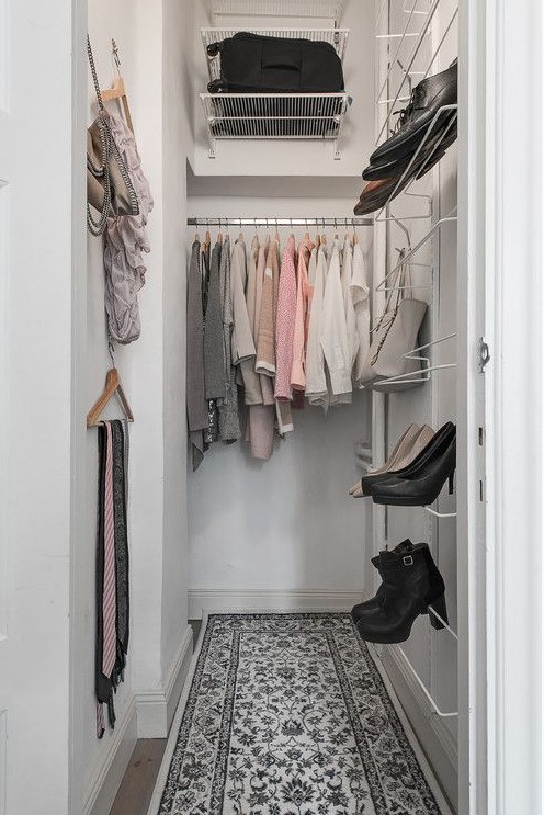 a small and narrow closet with a bit of open storage space and metal shelving, some clothes hangers on the wall is well-organized
