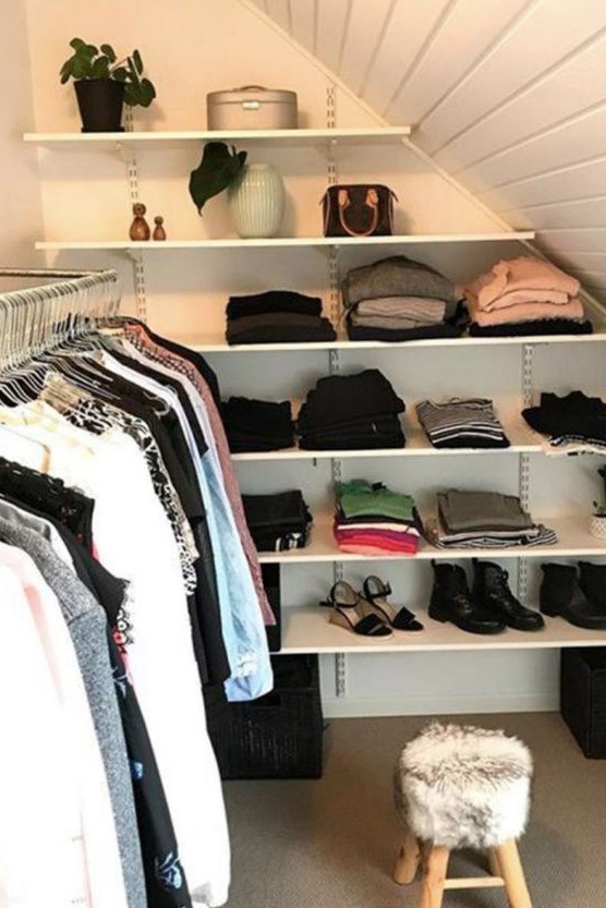 a small attic closet with open shelves and railings to hang some clothes plus a small pouf is a practical idea