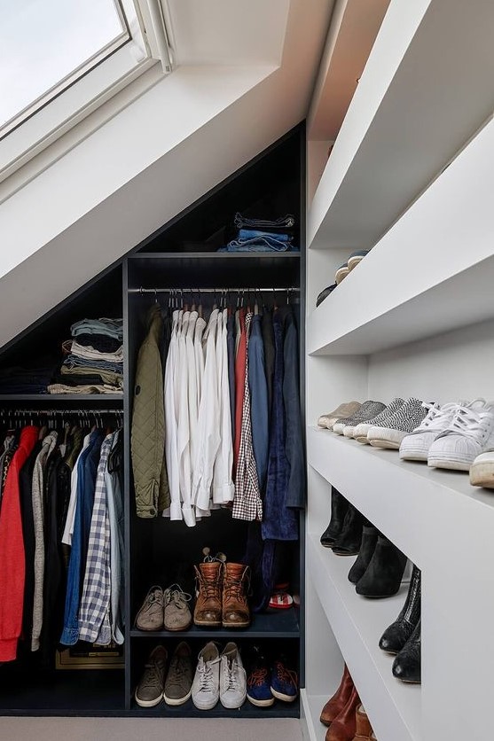 a small attic closet with open shelves for shoes, a navy open storage unit with railings and a skylight is a cool solution