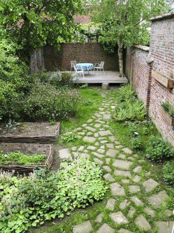 a small backyard garden with a grene lawn, some flower beds, greenery and shrubs plus a couple of trees