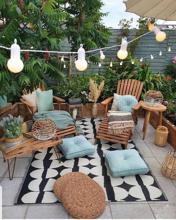 a small bright patio with a tiled floor, wooden furniture, coffee tables and side tables, candle lanterns and string lights over the space