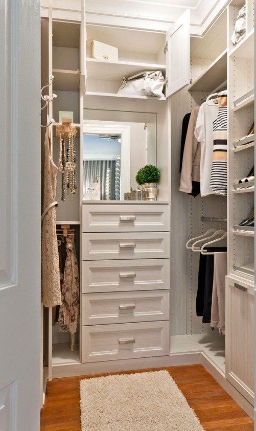 a small chic closet with built-in drawers, open storage compartments and shelves and built-in lights is a lovely space