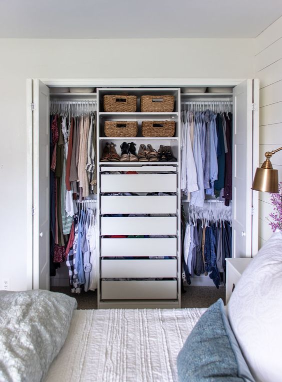 a small closet with rails and hangers, drawers and open shelves with baskets is a smart and cool solution for a bedroom