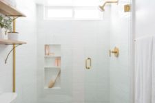 a small contemporary bathroom with white tiles in the shower, patterned tile floor, a navy vanity and touches of gold