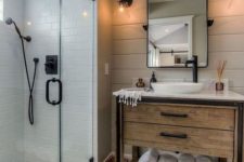 a small farmhouse bathroom with neutral tiles, patterned ones on the floor, a wooden vanity and black fixtures here and there
