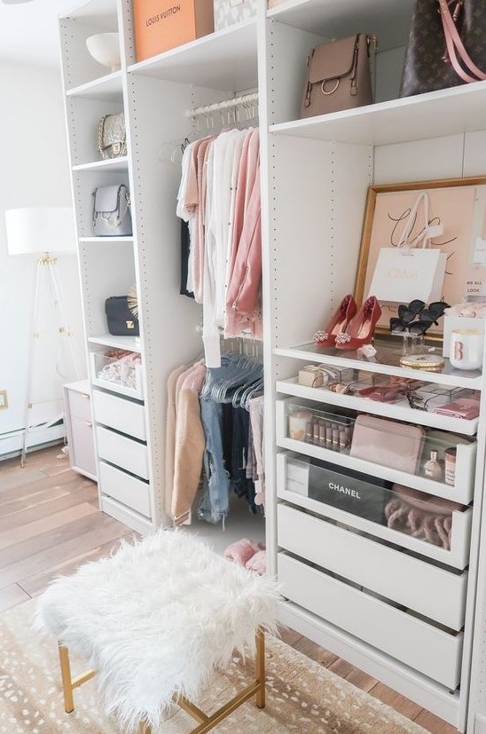 a small glam closet with holders and hangers, built-in drawers, open shelving, artworks, a faux fur stool and a printed rug