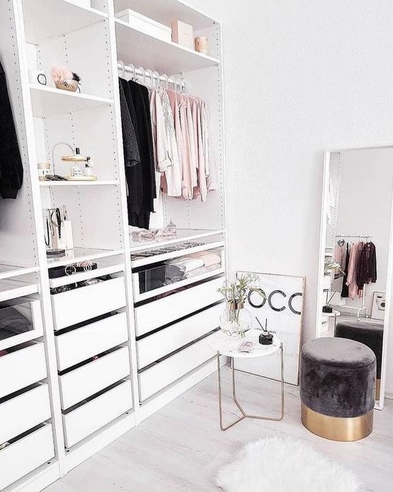 a small glam closet with shelves, a holder for hangers and some drawers, a large window and a cute suede ottoman