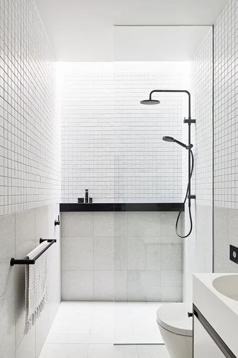 a small minimalist bathroom in black and white, with white small and large scale tiles, black fixtures and other touches