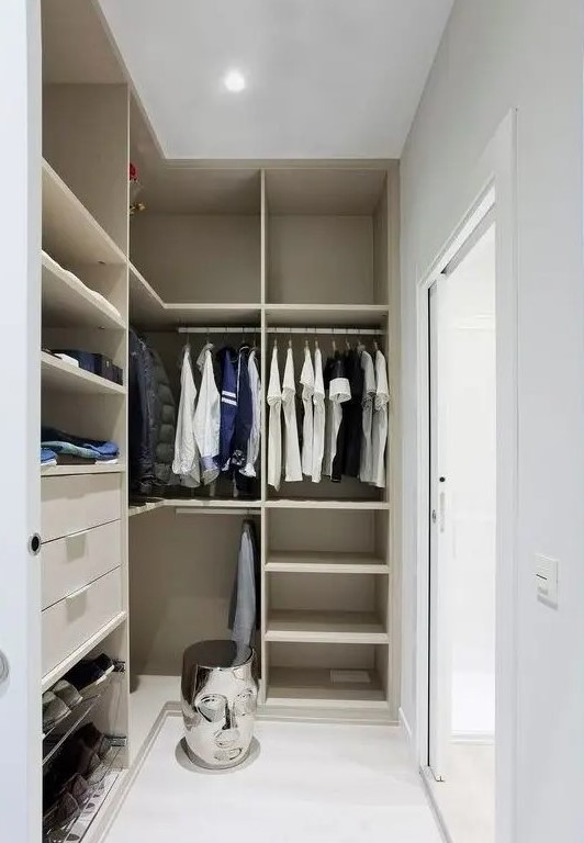 a small minimalist closet with lots of open storage space, dome drawers and holders for hangers, a creative stool and a glass sliding door