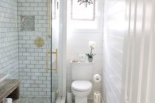 a small peaceful bathroom with white subway tiles, pritned floor, touches of gold and a star-shaped pendant lamp