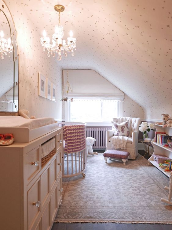 a small vintage-inspired attic nursery with a crystal chandelier, a large dresser, some furniture for the kid and adults