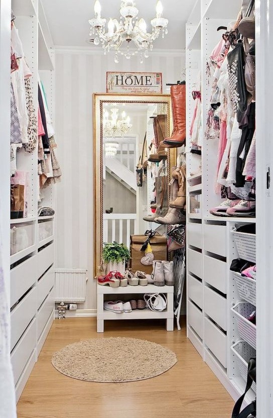 a small vintage-inspired sweet closet with a large mirror, a crystal chandelier, open shelves and holders plus drawers
