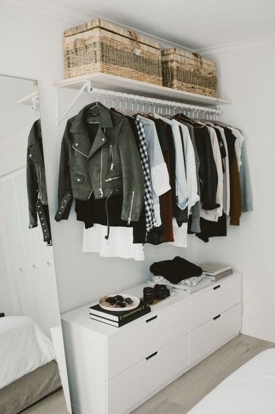 a small yet chic makeshift closet with a holder with hangers, a dresser, woven baskets can be placed in a bedroom