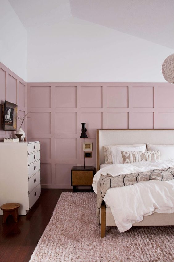 a stylish modern bedroom with white walls, pink paneling and a blush ceiling, a pink rug and neutral furniture