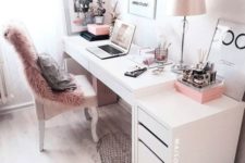 a stylish monochromatic home office with a faux fur cover, pink accessories and a pink lamp plus a graphic rug