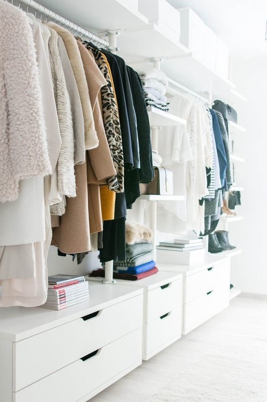 a stylish white minimalist closet with dressers, open shelves and holders for clothes hangers plus white boxes