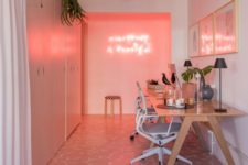 a super modern home office with a pink wall and neon lights, a pink gallery wall, a pink and white tile floor and sleek storage units