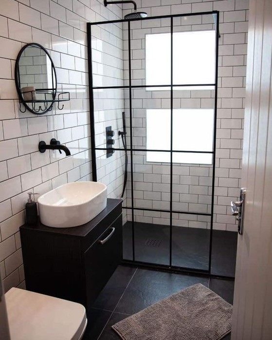 a tiny contrasting bathroom with windows in the shower, clad with white and black tiles, a black floating vanity and black touches here and there