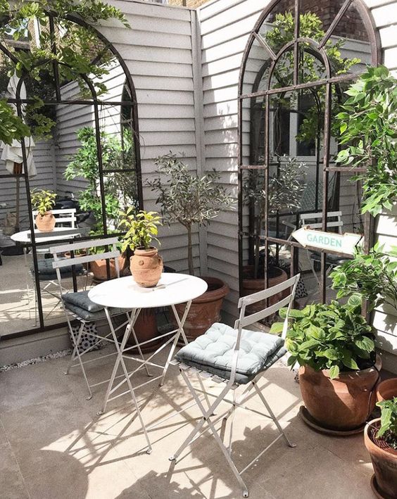 a tiny patio with folding garden furniture and lots of potted greenery around is a cool and cozy space