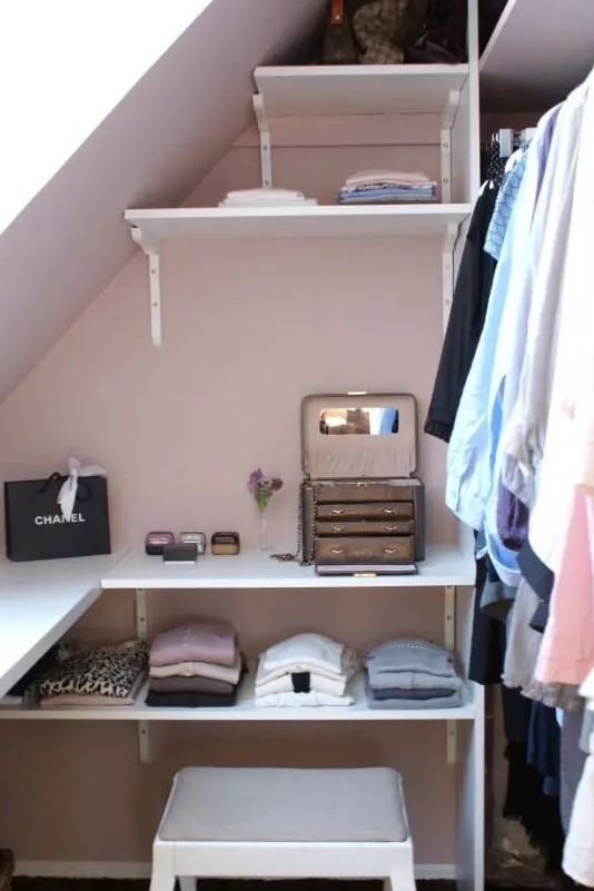 a tiny sloped walk-in closet with open shelves, a stool and railing for clothes is a lovely idea for a modern space
