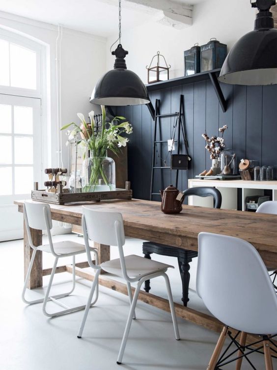 a vintage dining room with a black beadboard wall, black pendant lamps, a wooden table and white chairs looks chic