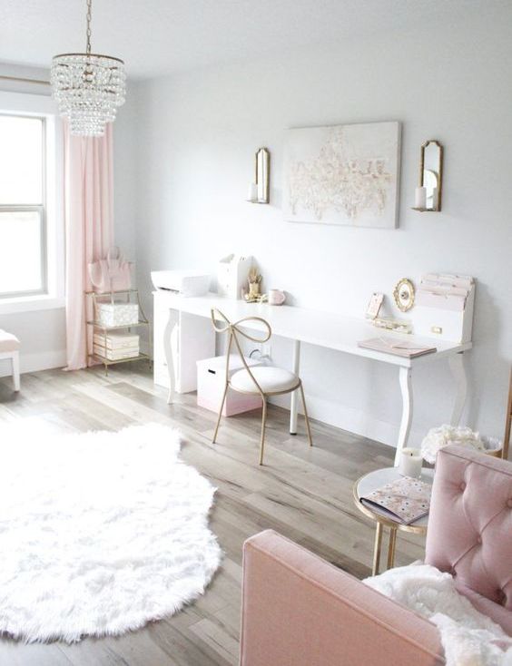 an airy and ethereal home office with white walls, pink curtains, pink furniture and some accessories plus a crystal chandelier