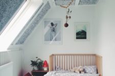 an attic nursery with a mint floor, a black and white paneled ceiling, a crib and some toys and storage units