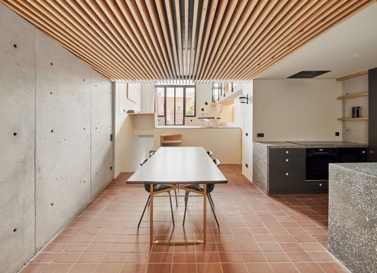 The kitchen and dining space are united, the kitchen is done with grey cabinets and the dining zone shows off a wooden table and black chairs The kitchen and dining space are united, the kitchen is done with grey cabinets and the dining zone shows off a wooden table and black chairs
