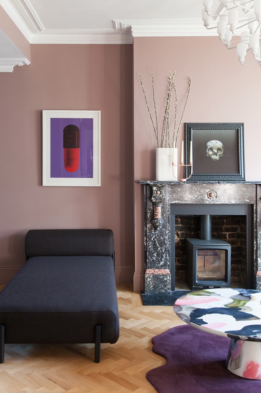 The living room features mauve walls, a mini hearth in the non-working fireplace and catchy artworks