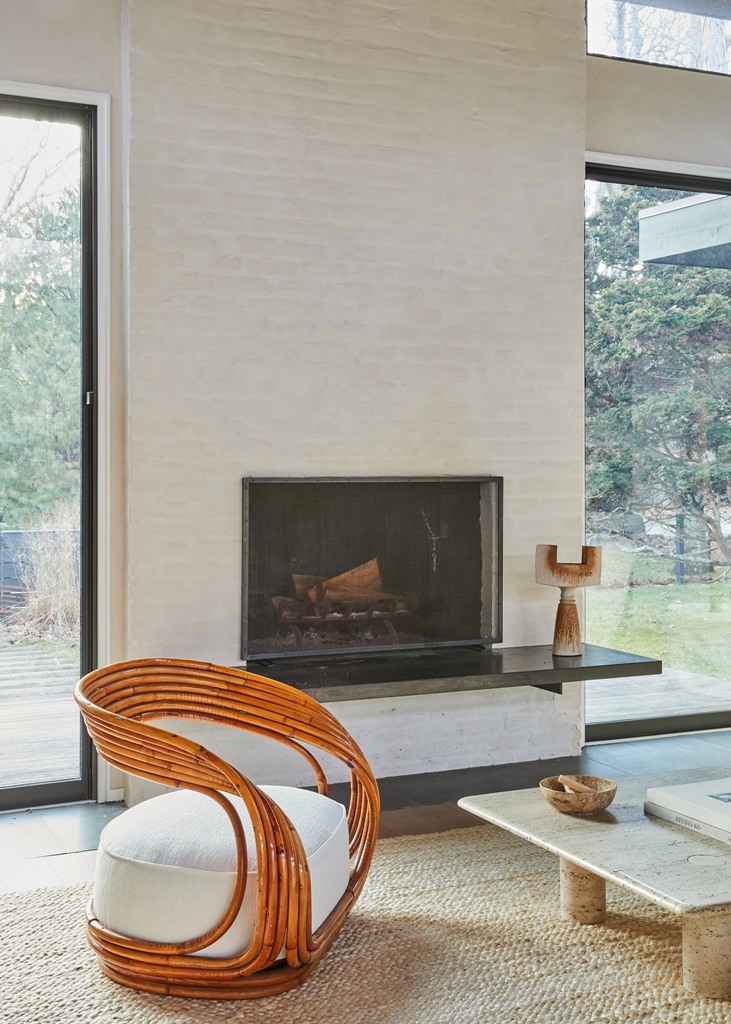 The walls are covered with white plaster, the fireplace is done with brick, and the floor is dark