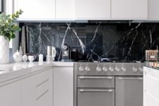 02 a black marble kitchen backsplash is a very luxurious touch to these ultra-minimalist white cabinets