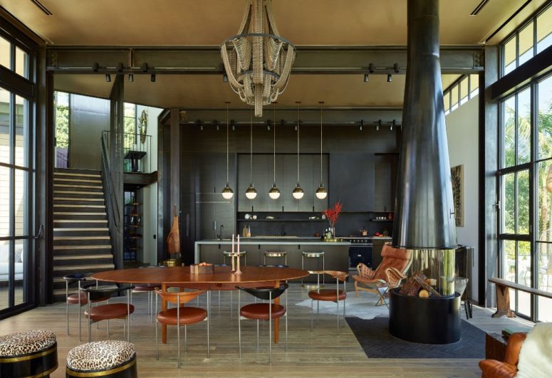 The kitchen is all dark, with refined pendant lamps and the dining zone features a cool hearth and a fantastic gold chandelier