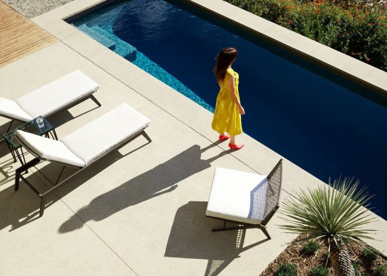 There's a long and narrow pool and white loungers and chairs by its side