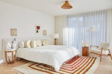 06 The master bedroom is mid-century modern, mostly neutral but with a striped rug and touches of wicker and stone