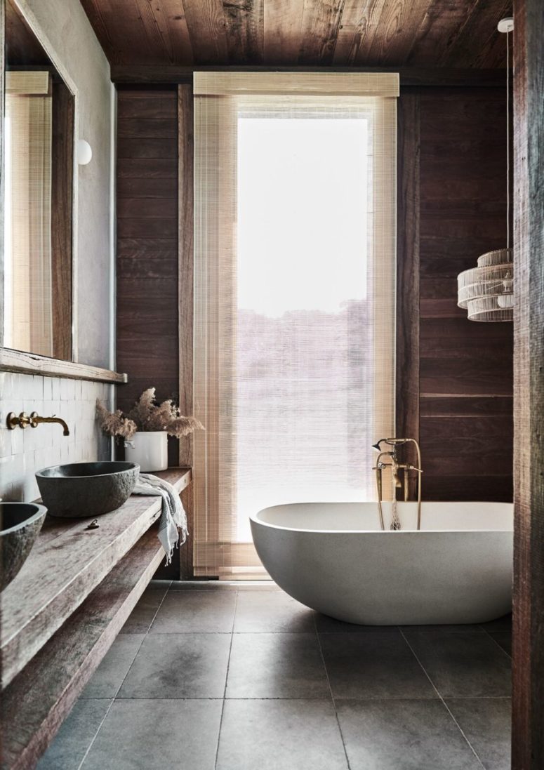 This bathroom features much natural wood, tiles, a white stone tub and even some views