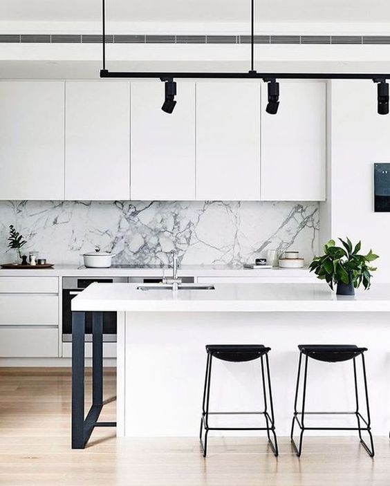 a chic white minimalist kitchen with touches of black for more drama and a white marble backsplash for a refined feel